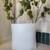 Platte metalen vaas in off white met ruwe afwerking van 37 cm op de vensterbank