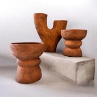 Roestbruine buitenpotten en vaas met matte afwerking op terras met planten